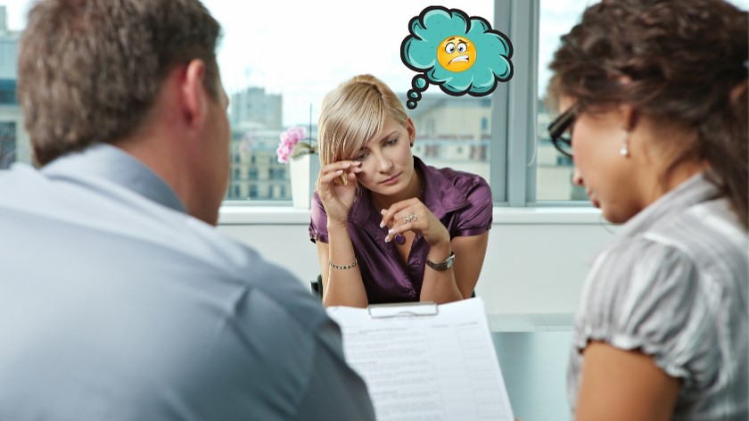 A woman discusses with a man and another woman during a job interview setting.